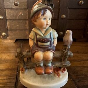 Little boy sitting on fence with a bird